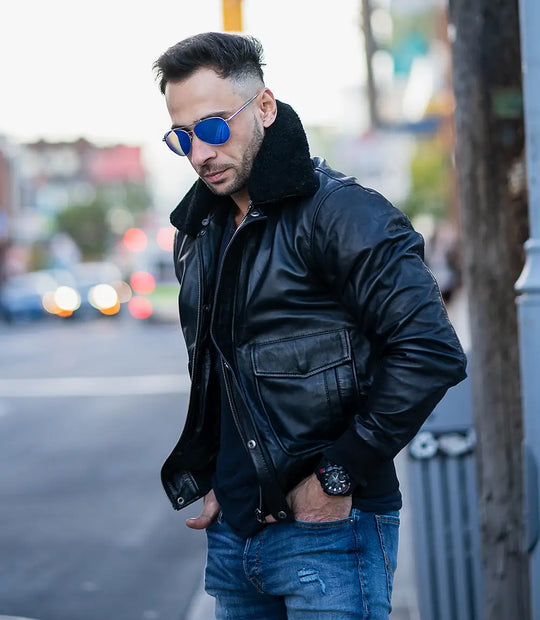 Lifestyle shot of a man wearing a black A2 Bomber Aviator leather jacket with a black shearling collar in an urban street setting.