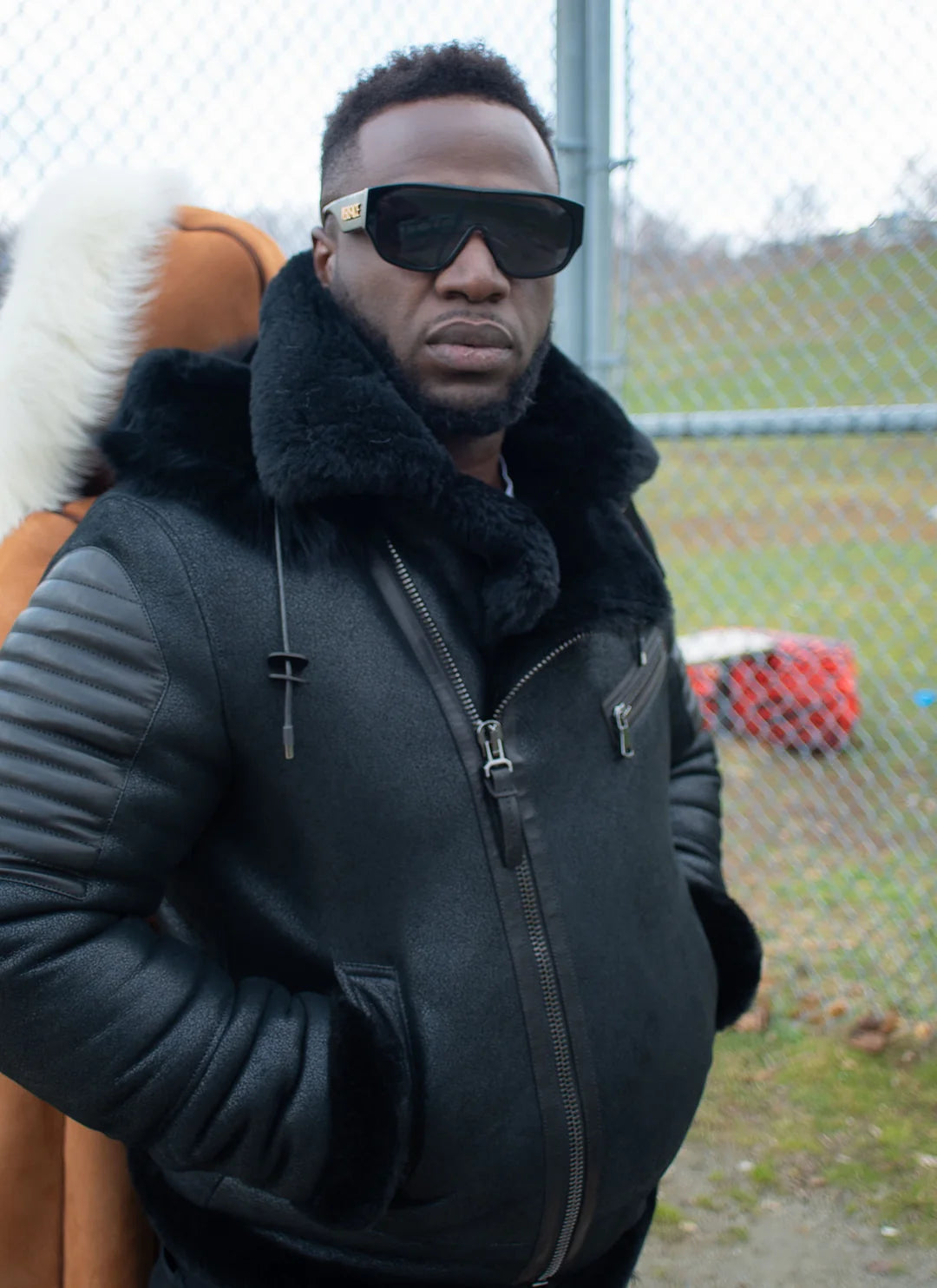 Model wearing the Lucas Black Aviator Bomber Shearling Jacket with Hoodie in an outdoor lifestyle setting, highlighting the stylish fit and functional design.