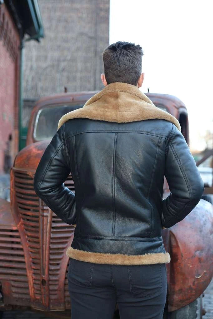 Person wearing a Graysen black Aviator bomber shearling jacket back pose with fur trim standing in front of an old truck.