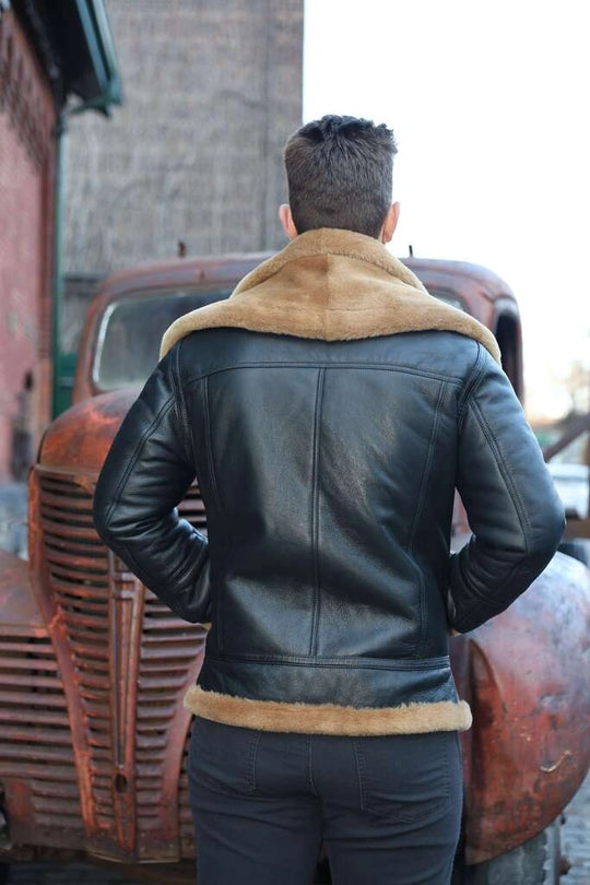 Person wearing a Graysen black Aviator bomber shearling jacket back pose with fur trim standing in front of an old truck.