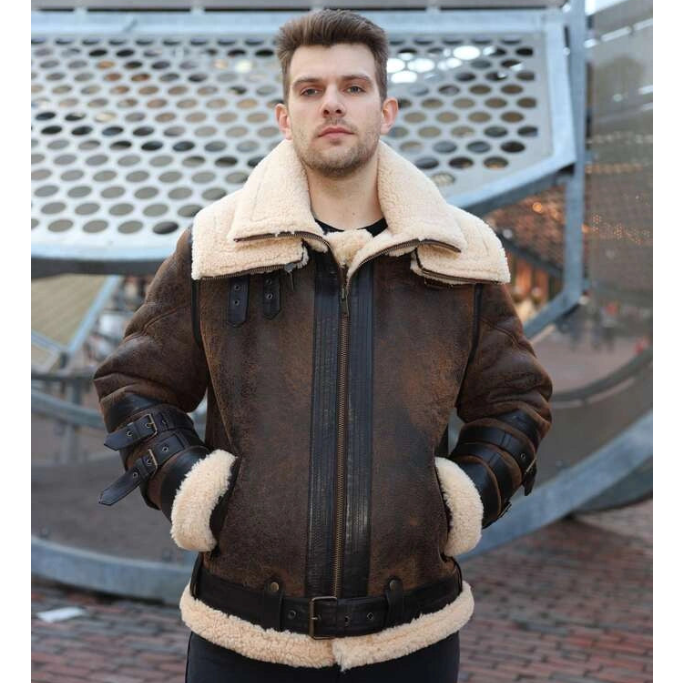 Man wearing a brown leather jacket with white fur lining standing in front of a metal structure.