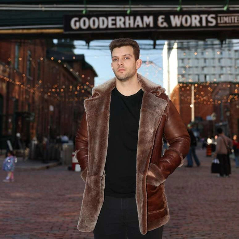 Man wearing a brown shearling coat standing in front of a 'Gooderham & Worts' sign.
