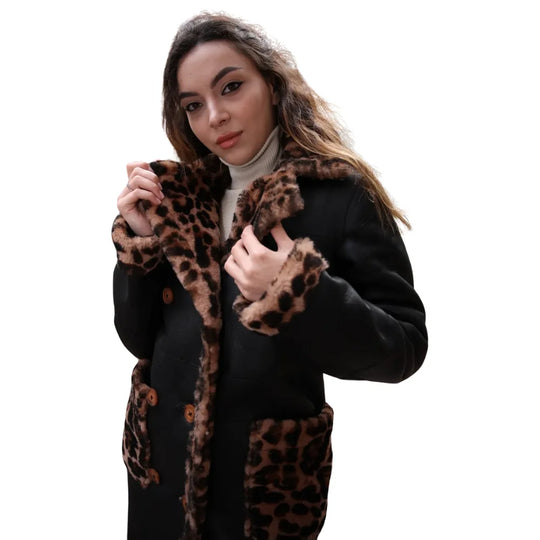 A model wearing the oversized Seraphina leopard print leather coat styled with black trousers, demonstrating the mid-thigh length and relaxed fit.