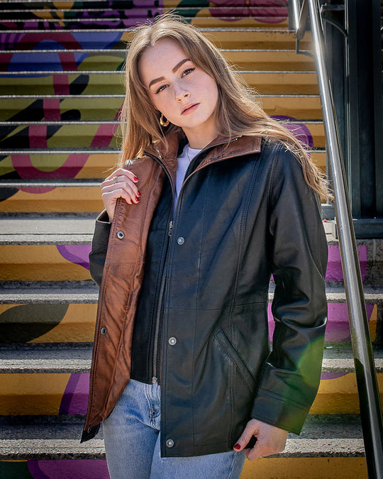 Lifestyle photoshoot of a woman wearing the Adeline black leather car coat, showcasing its elegant 3/4 length and regular fit on colorful steps.