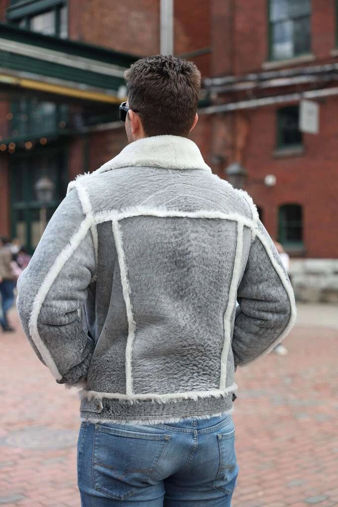 Person wearing a gray shearling jacket with white trim in an urban setting
