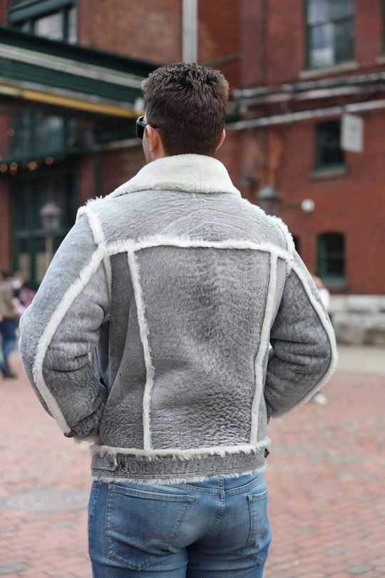 Person wearing a gray shearling jacket with white trim in an urban setting
