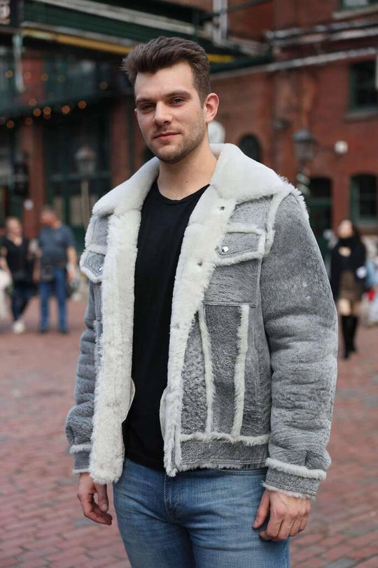 Man wearing a Aidens distressed gray shearling jacket with white fur trim outdoors.