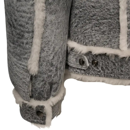 Close-up view of the sleeve cuff of Aiden's Distressed Grey Shearling Trucker Jacket, showcasing the white shearling lining and button detailing on the cuff. The fabric has a rugged, distressed grey texture with soft faux fur accents.