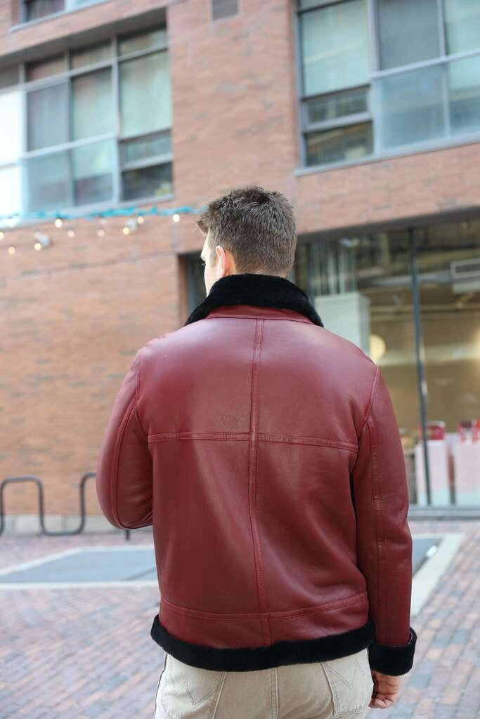 Person wearing Aurelius Burgundy B3 Bomber Jacket standing on a city street.