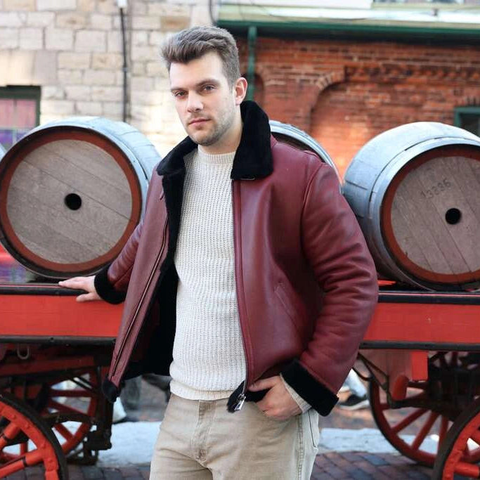 Man in Aurelius Burgundy B3 Bomber Jacket standing next to wooden barrels on a cart.