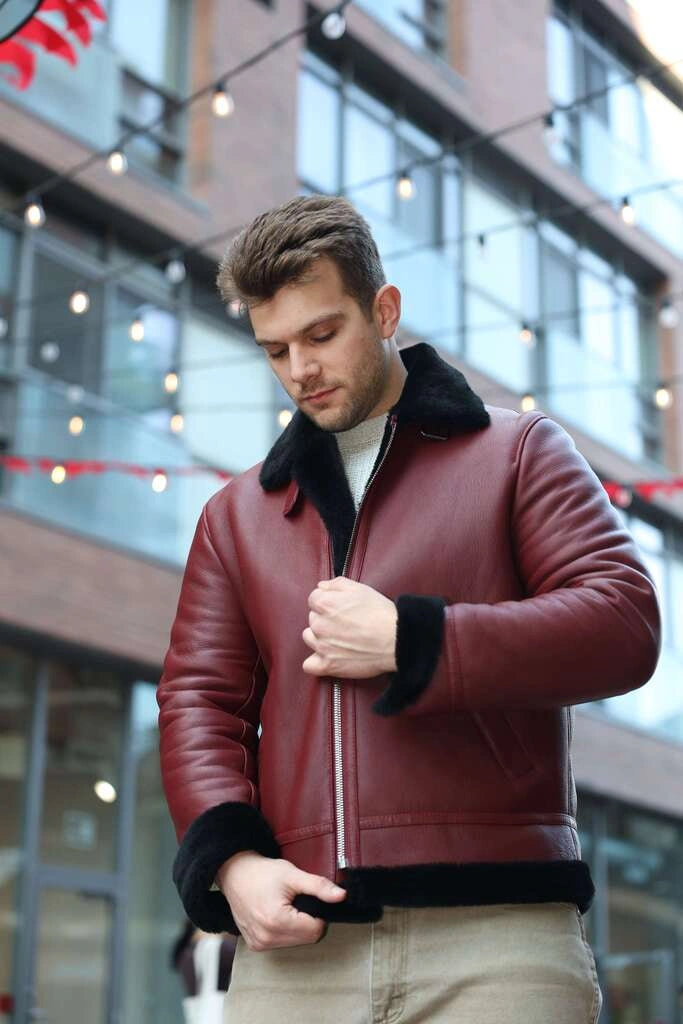 Man wearing Aurelius Burgundy B3 Bomber Jacket with black fur trim in an outdoor setting.
