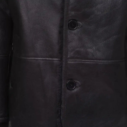 Close-up of a black shearling trench coat with button details.