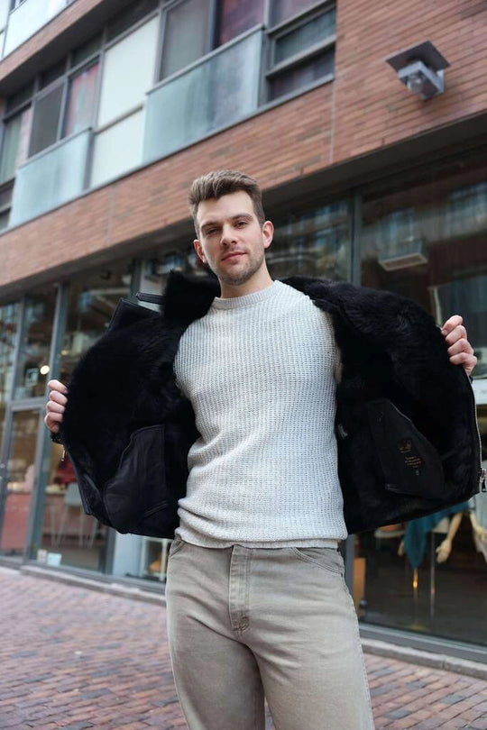 Man holding a Carter's Toscana Shearling Leather Biker Jacket's interior outdoors in front of a building