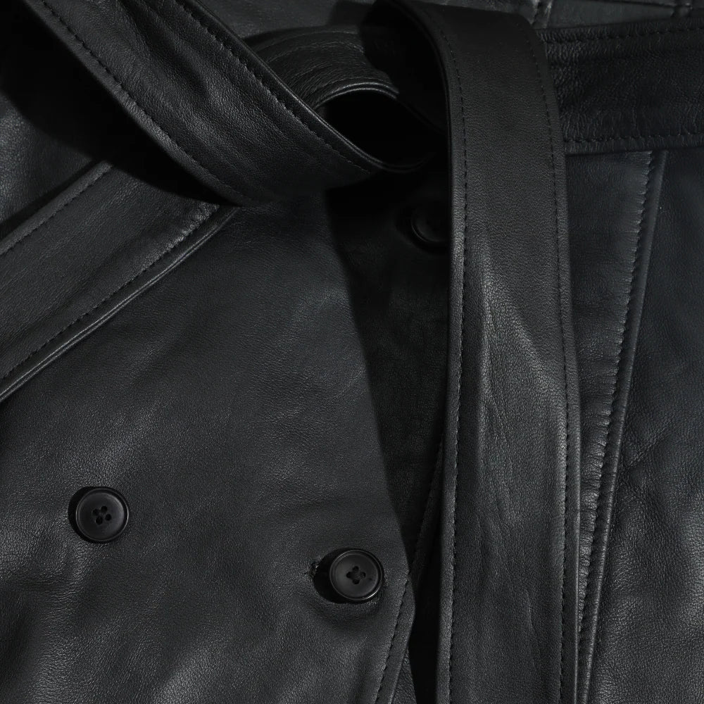 Close-up of a black leather coat with buttons and a strap.
