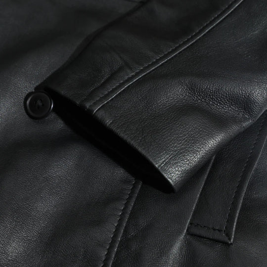 Close-up of a black leather coat sleeves with a button