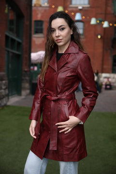 Woman wearing a red leather coat standing in front of a brick building.