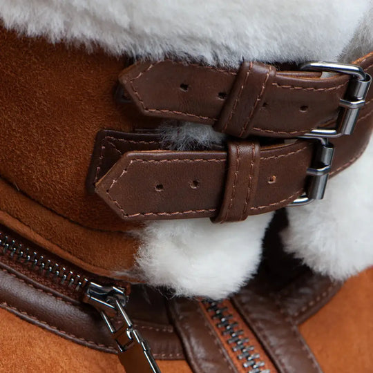 Detailed shot of Hagan's Tan Suede Jacket, showcasing the cream shearling collar and stylish leather buckles on the sleeves. The warm shearling provides a luxurious touch, paired with the durable suede leather for a classic aviator design.