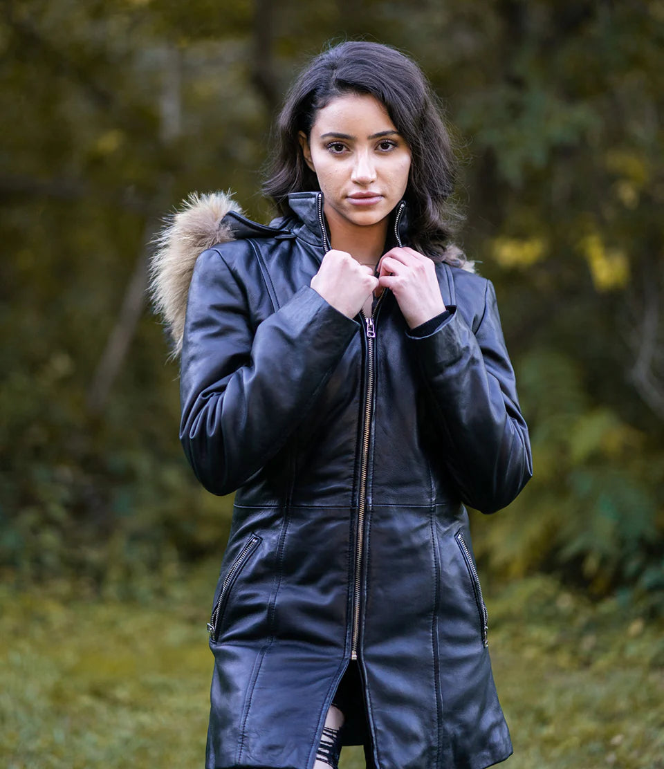 Woman Side profile in Jazmyn's long winter coat, emphasizing the thick fox fur hood and the protective longline fit in a forest setting.