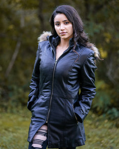 Woman posing in Jazmyn's long winter coat, the protective longline fit in a forest setting.