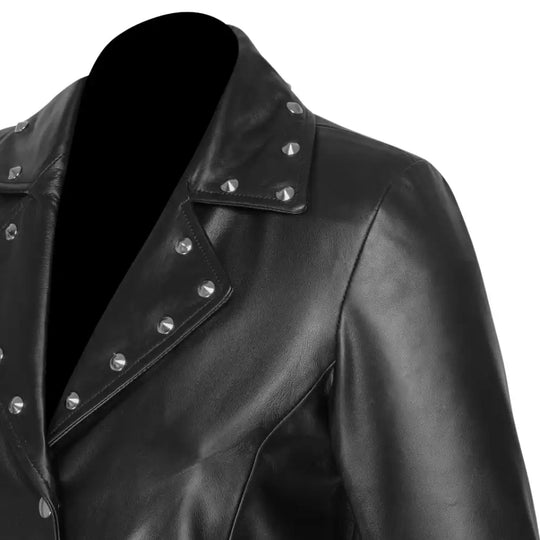 Close-up of the neckline and shoulder construction with studded details of the Jennifer asymmetrical dress on a white background.