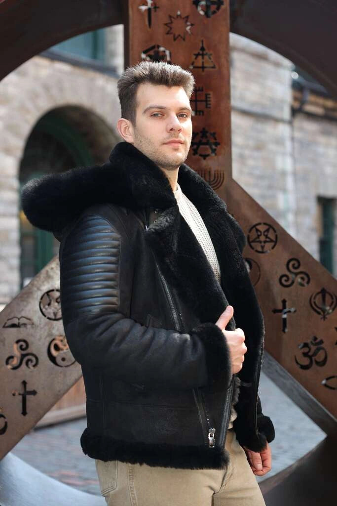 Man wearing Lucas Black Aviator Bomber Shearling Jacket with fur trim standing in front of decorative metalwork.