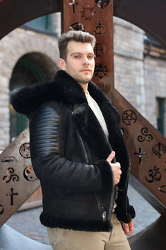 Man wearing Lucas Black Aviator Bomber Shearling Jacket with fur trim standing in front of decorative metalwork.