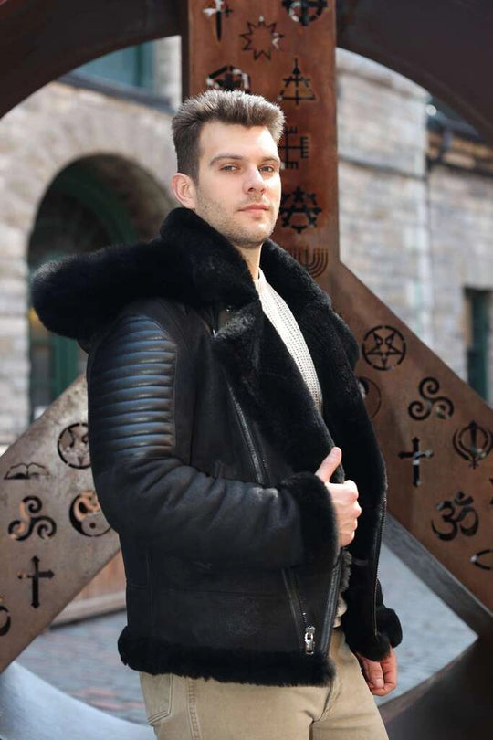 Man wearing Lucas Black Aviator Bomber Shearling Jacket with fur trim standing in front of decorative metalwork.
