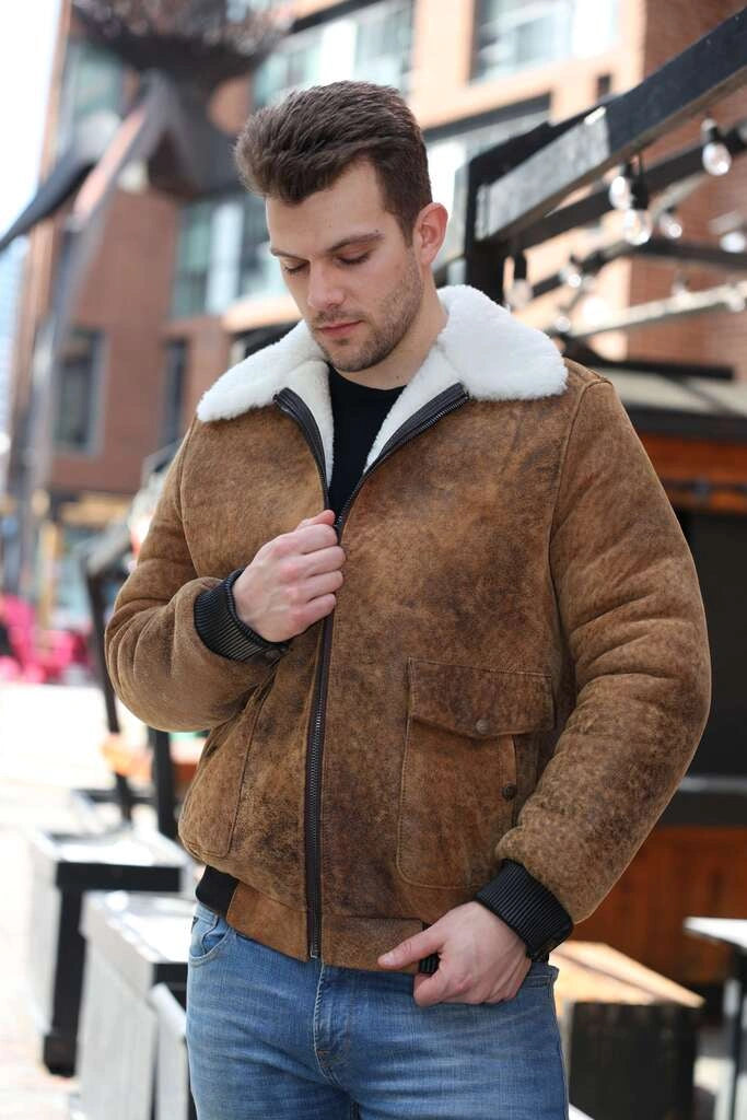 Man wearing Lucian's distressed brown A2 Bomber shearling jacket with white fur lining outdoors.