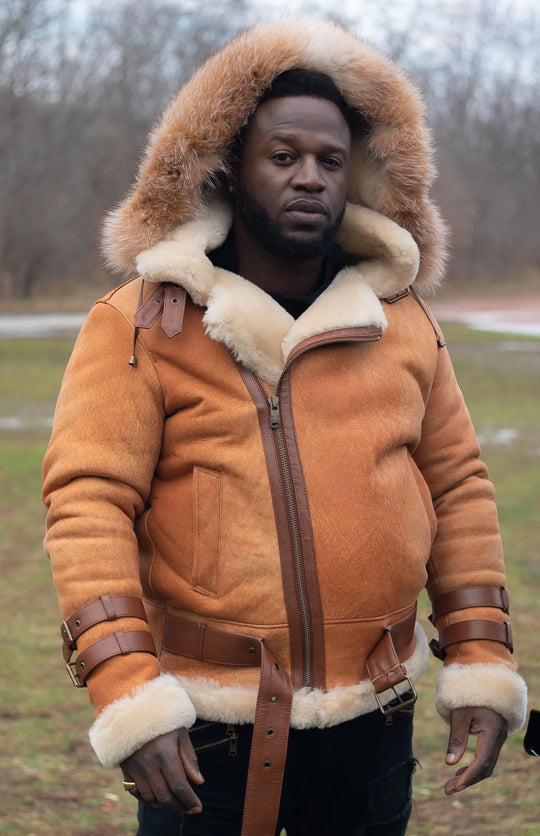 Man wearing a Cognac shearling aviator jacket with fur trim outdoors in a winter setting.