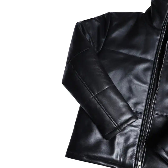 Close-up of the Sorine jacket’s premium black leather, highlighting the soft sheen, fine stitching, and concealed zipper pockets.
